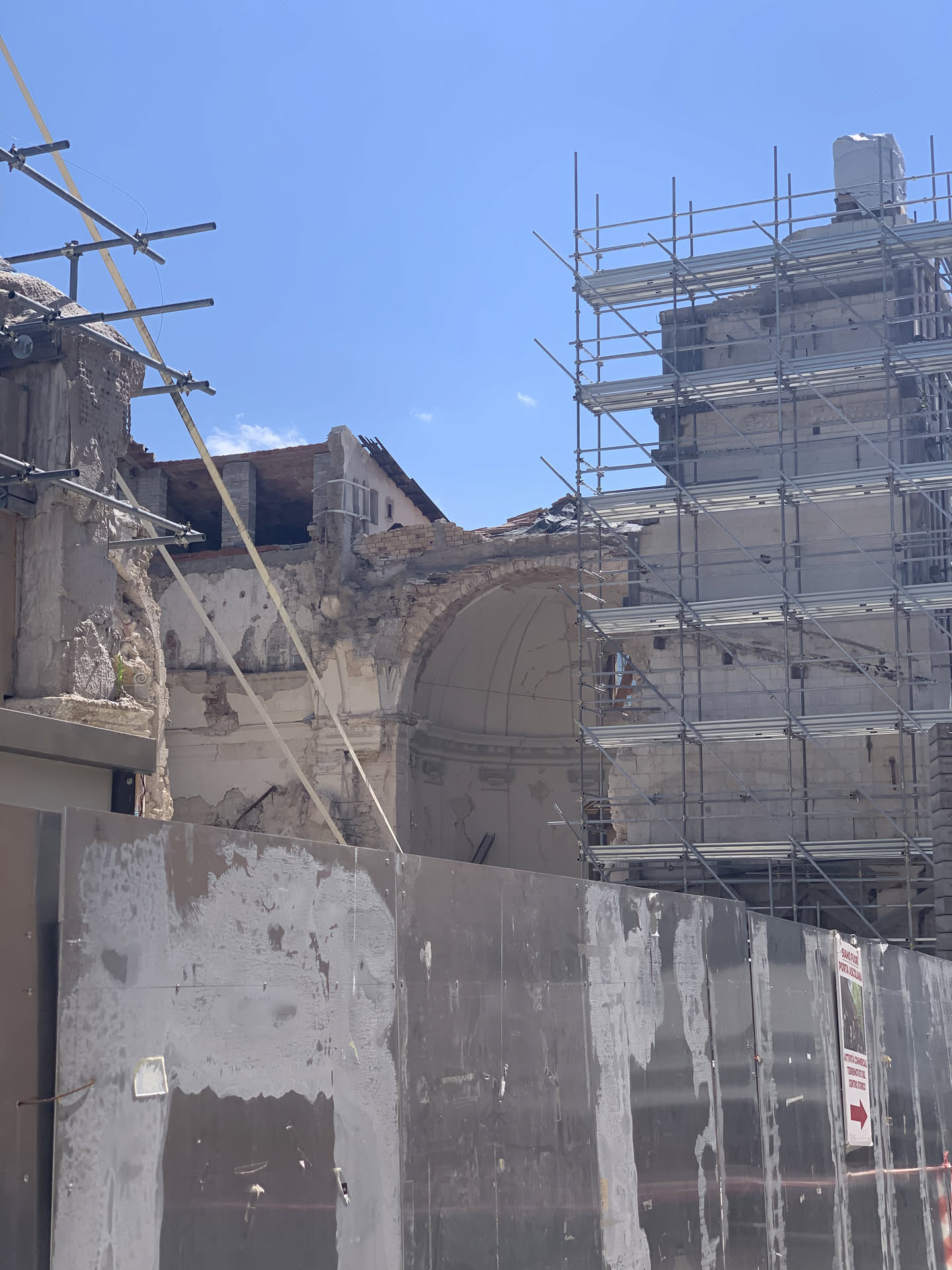 Le macerie della basilica nel 2020: muri aperti in sezione, una volta absidale rimasta appesa con l'intonaco ancora attaccato, ponteggi tutt'intorno