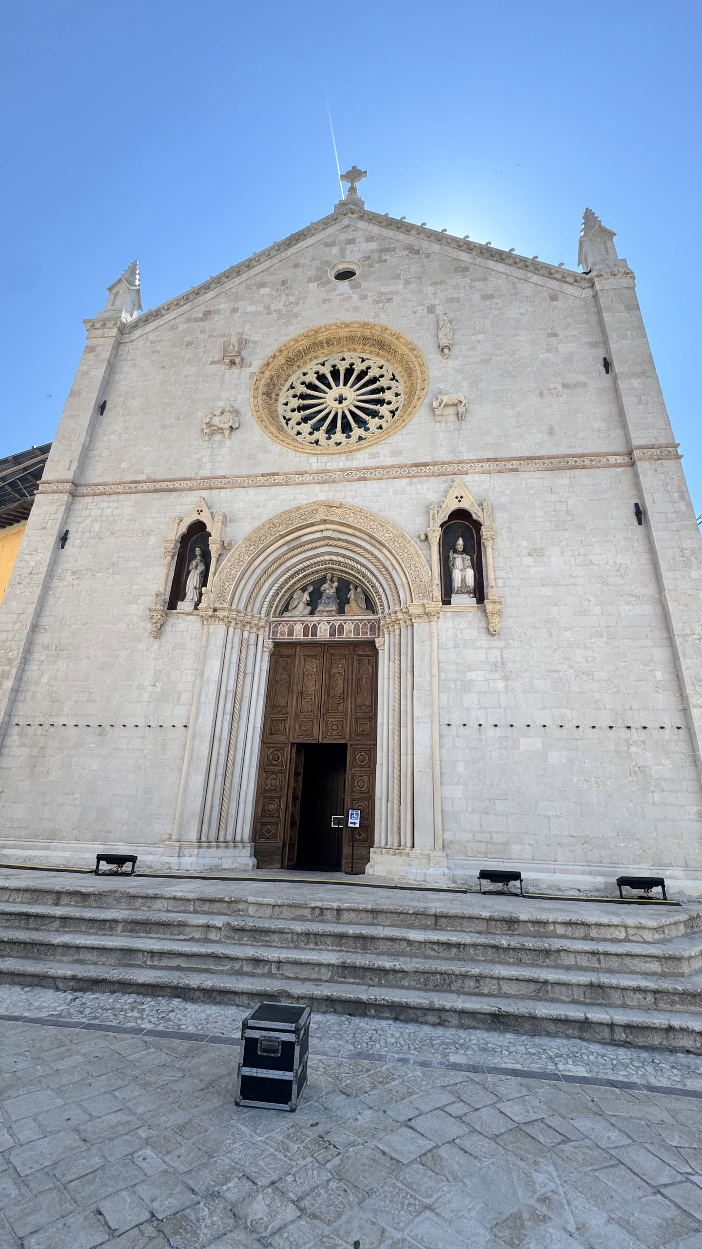 Luglio 2026: la facciata gotica della basilica libera da ponteggi, vista dal basso, con il rosone, le statue nelle nicchie e il portale spalancato