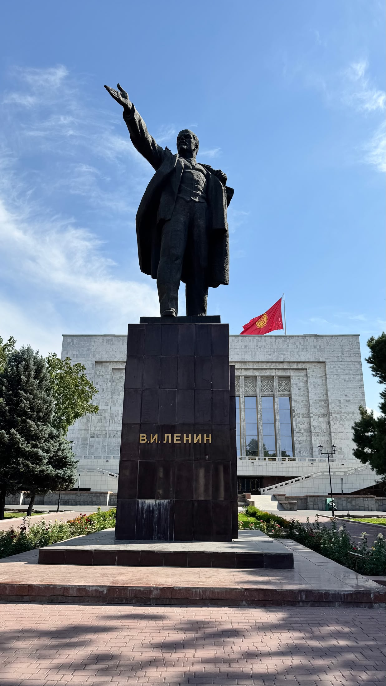 La statua di Lenin col braccio teso, spostata dietro al Museo Nazionale di Storia, con la bandiera kirghisa sulla destra