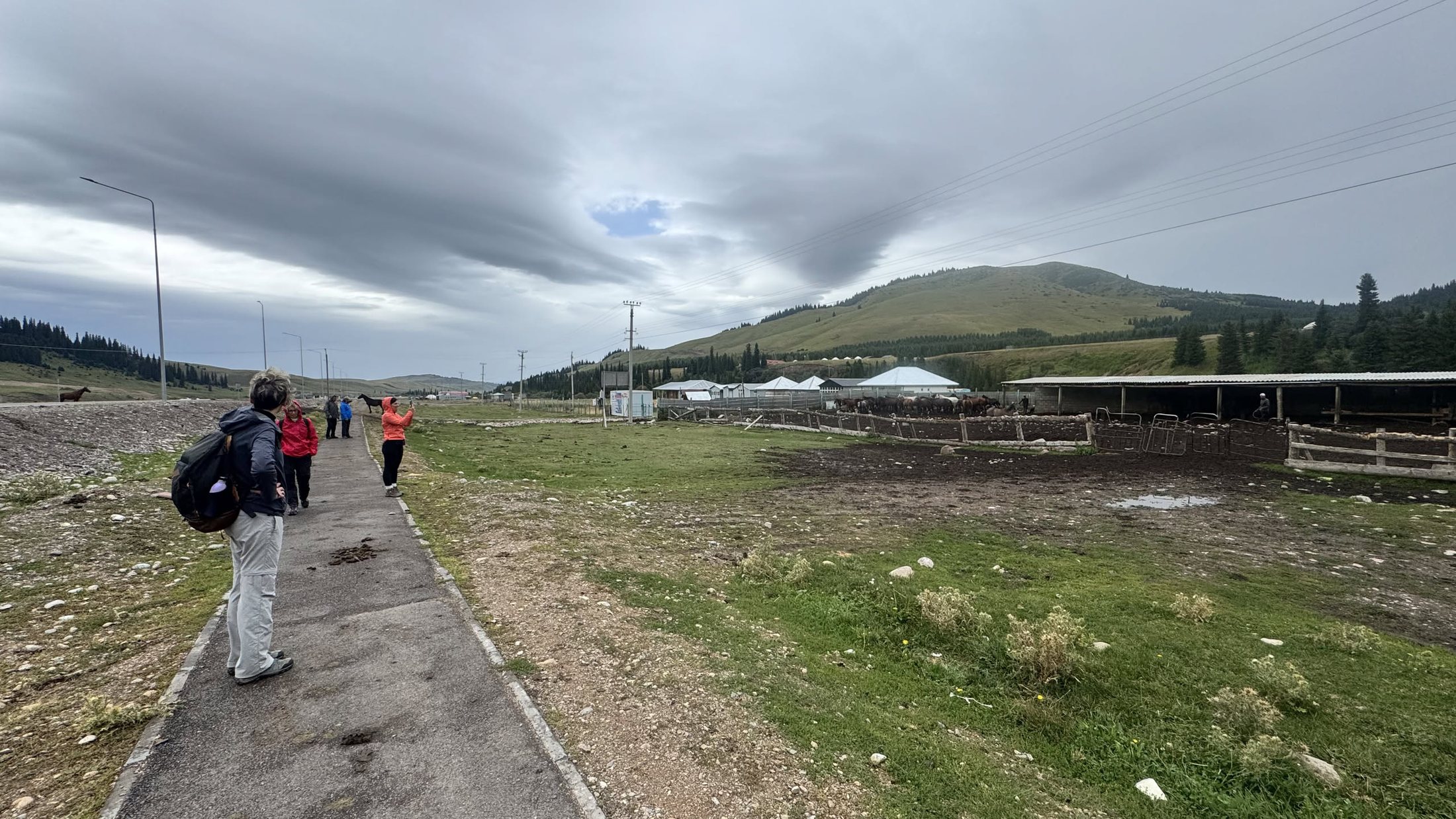 Si parte a piedi: la stradina verso il fondovalle, le nuvole a coperchio e il campo che resta indietro