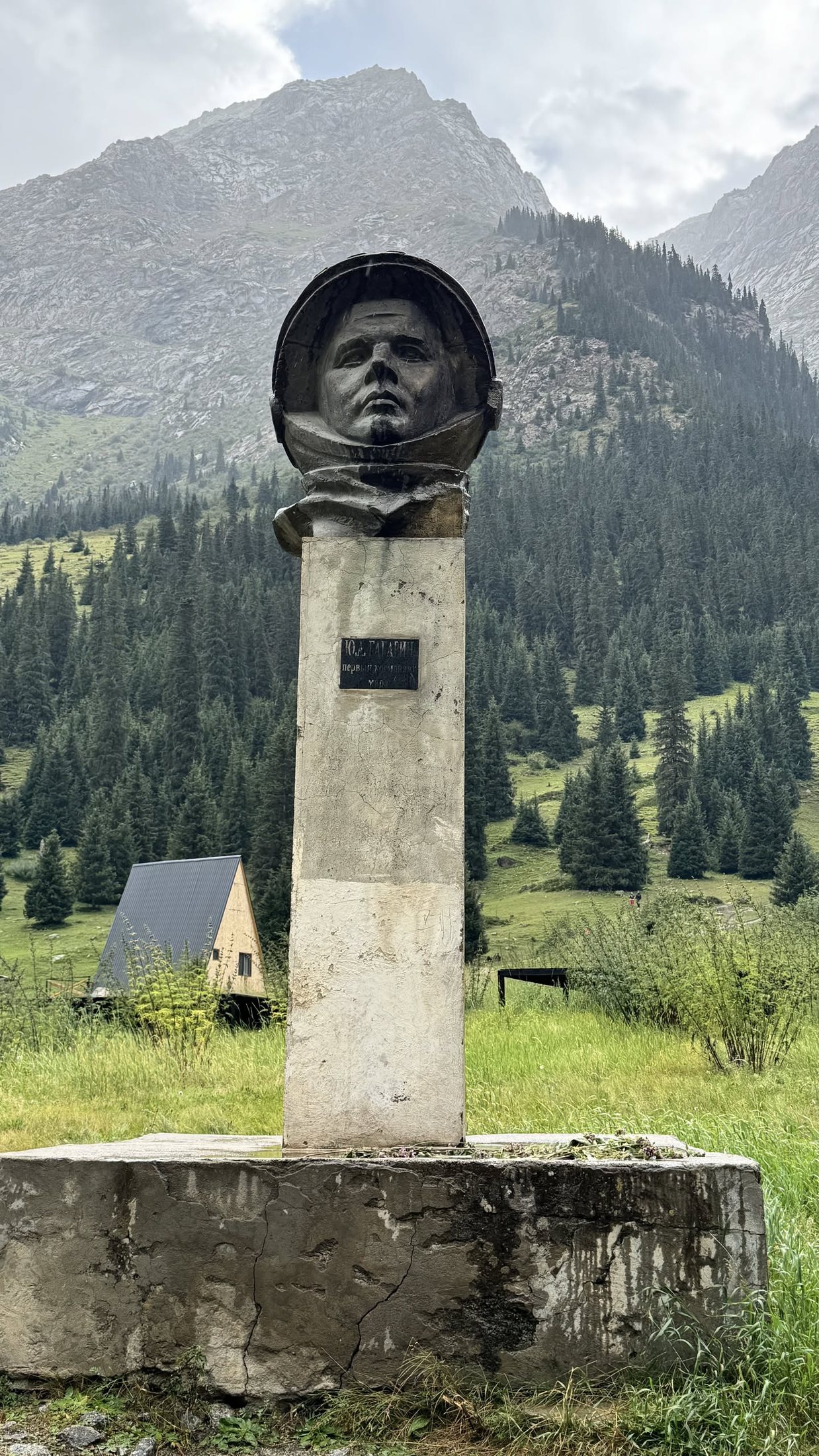 Il busto sulla stele, con la valle che si chiude dietro.