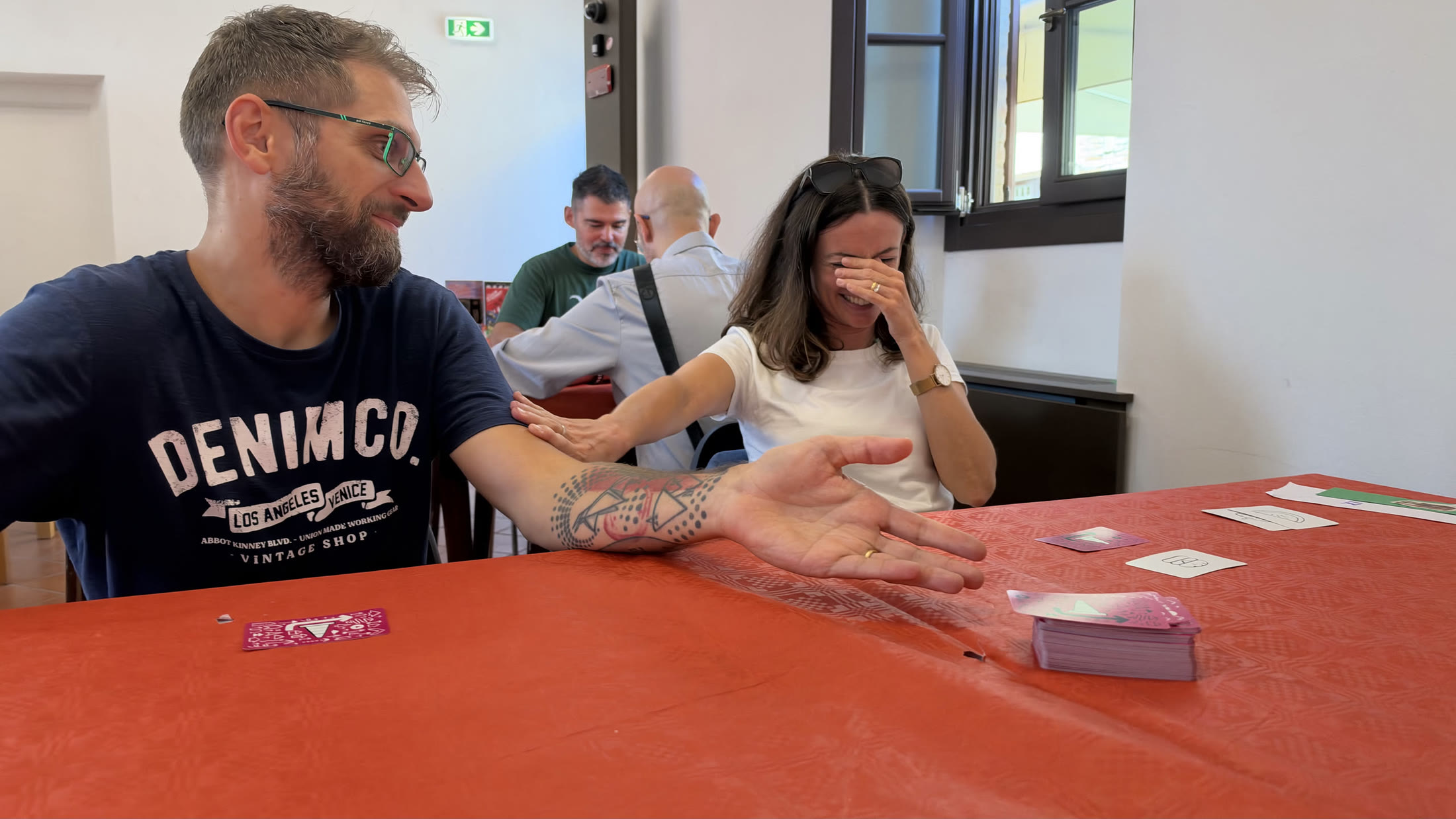 Il regalo passa di mano sulla tovaglia rossa di Gradara Ludens: chi lo riceve deve decidere se fidarsi.