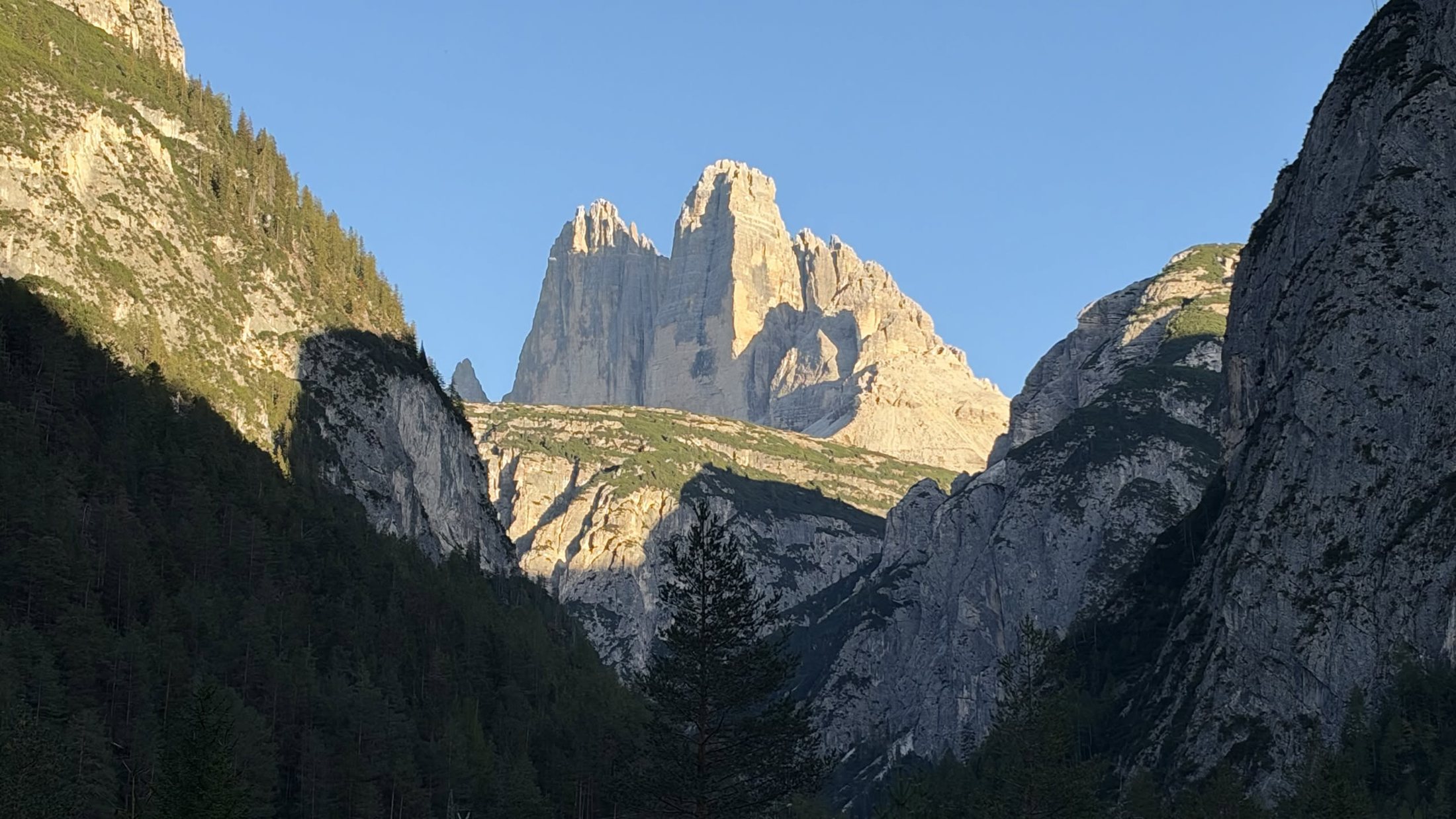 Al ritorno, a Landro: le Tre Cime accese dall'ultimo sole, la valle già in ombra
