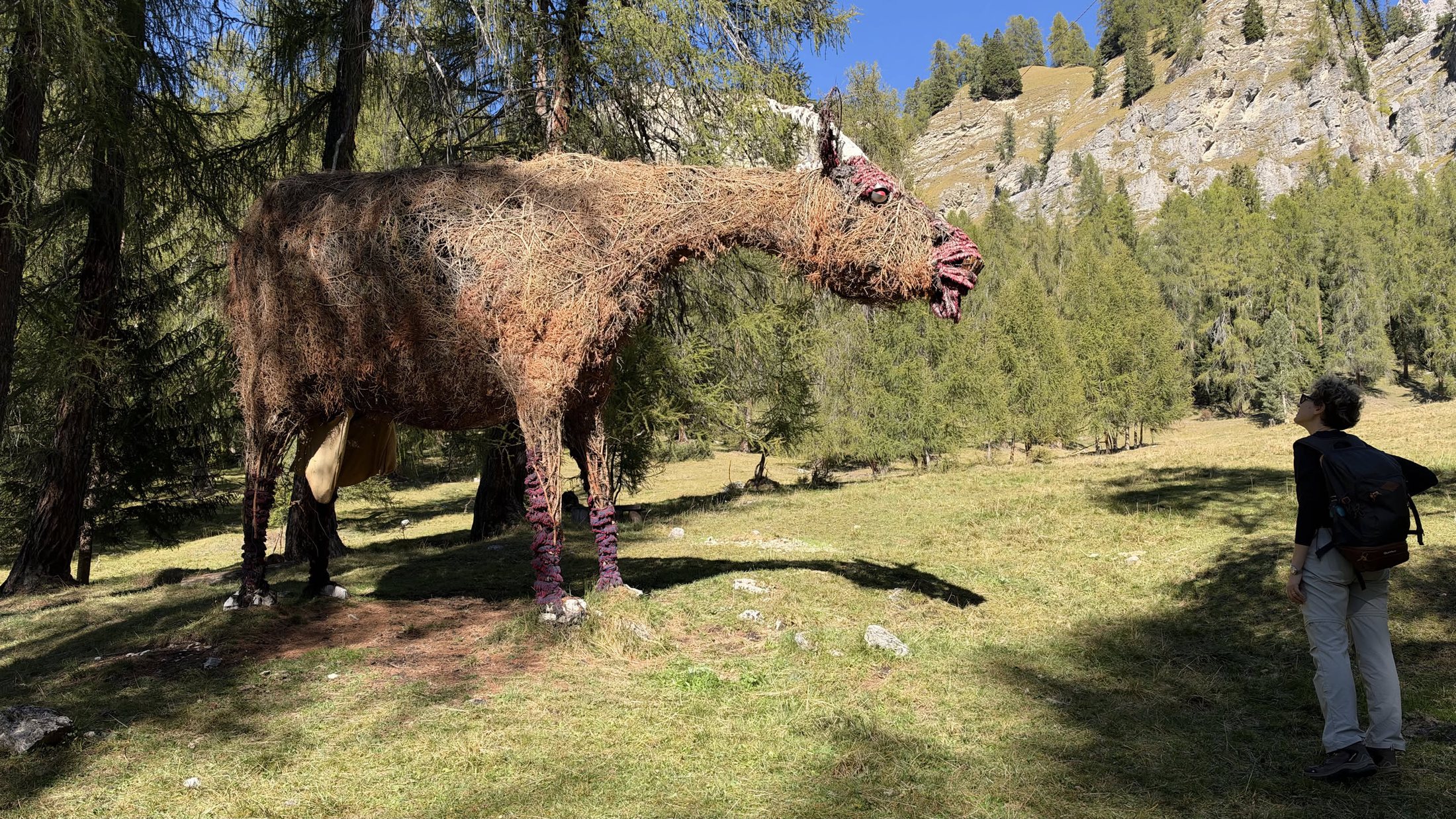E poi, in mezzo al prato, lei: una mucca di rami e fieno alta come una stanza