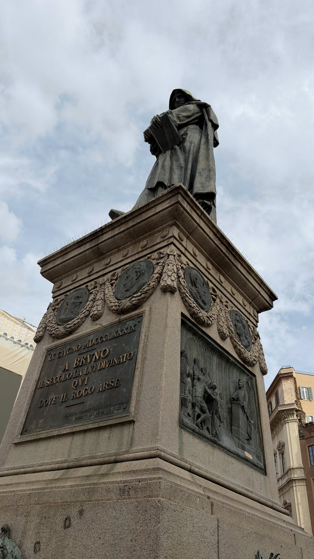 Giordano Bruno a Campo de' Fiori, incappucciato e rivolto verso il Vaticano.