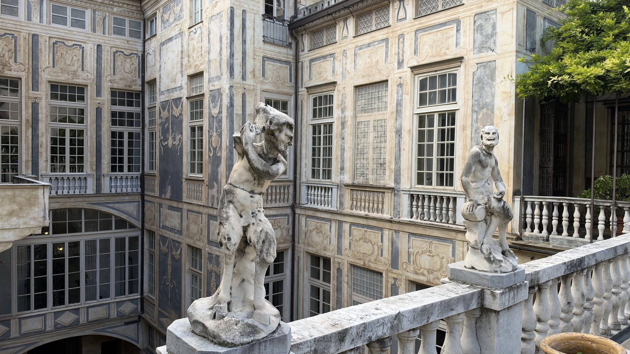 Le statue sulla balaustra sopra il cortile, contro le facciate dipinte del palazzo.
