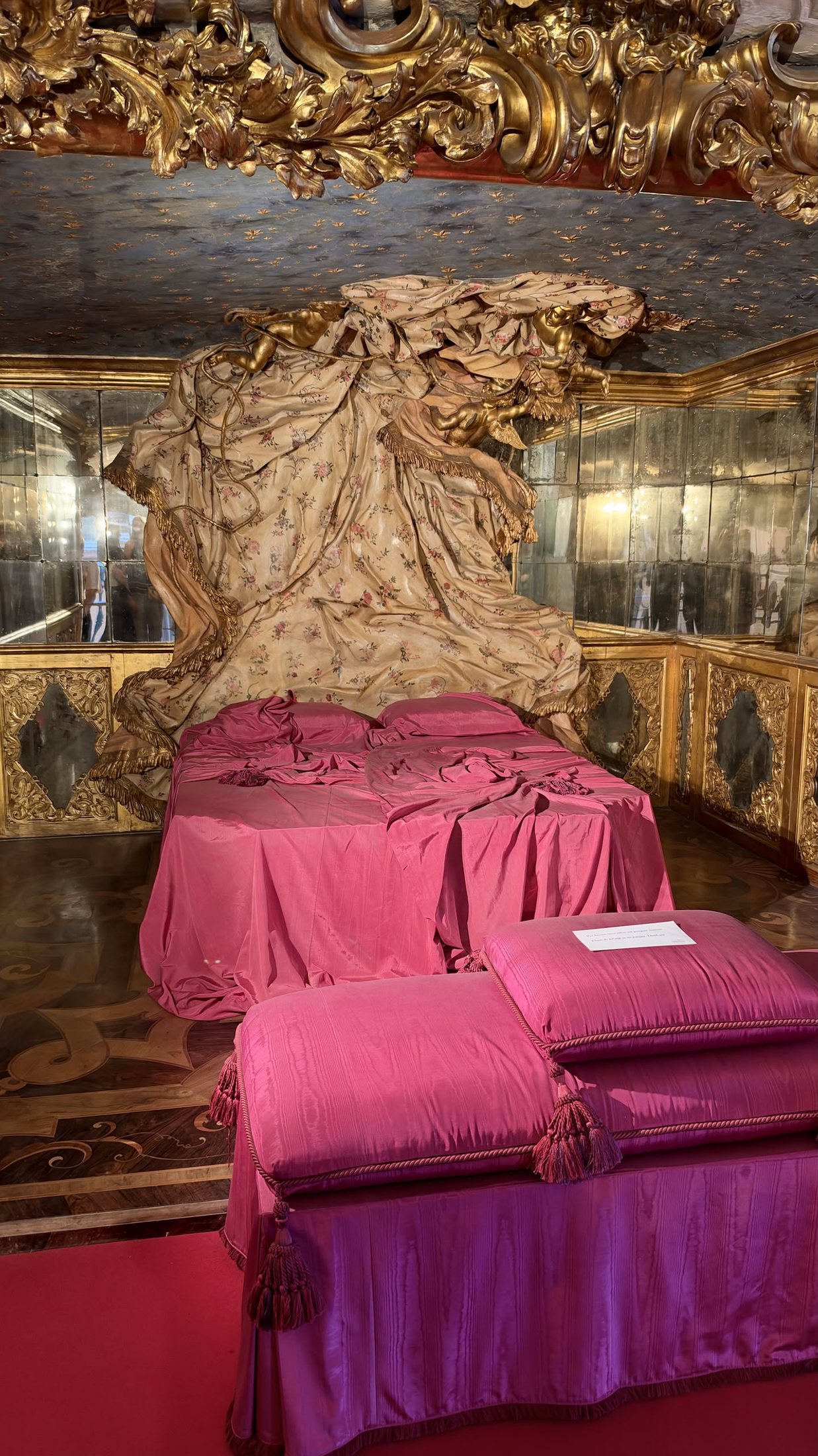 L'alcova delle mezzarie di Palazzo Rosso: il letto rosa, gli specchi e il drappo di stucco.