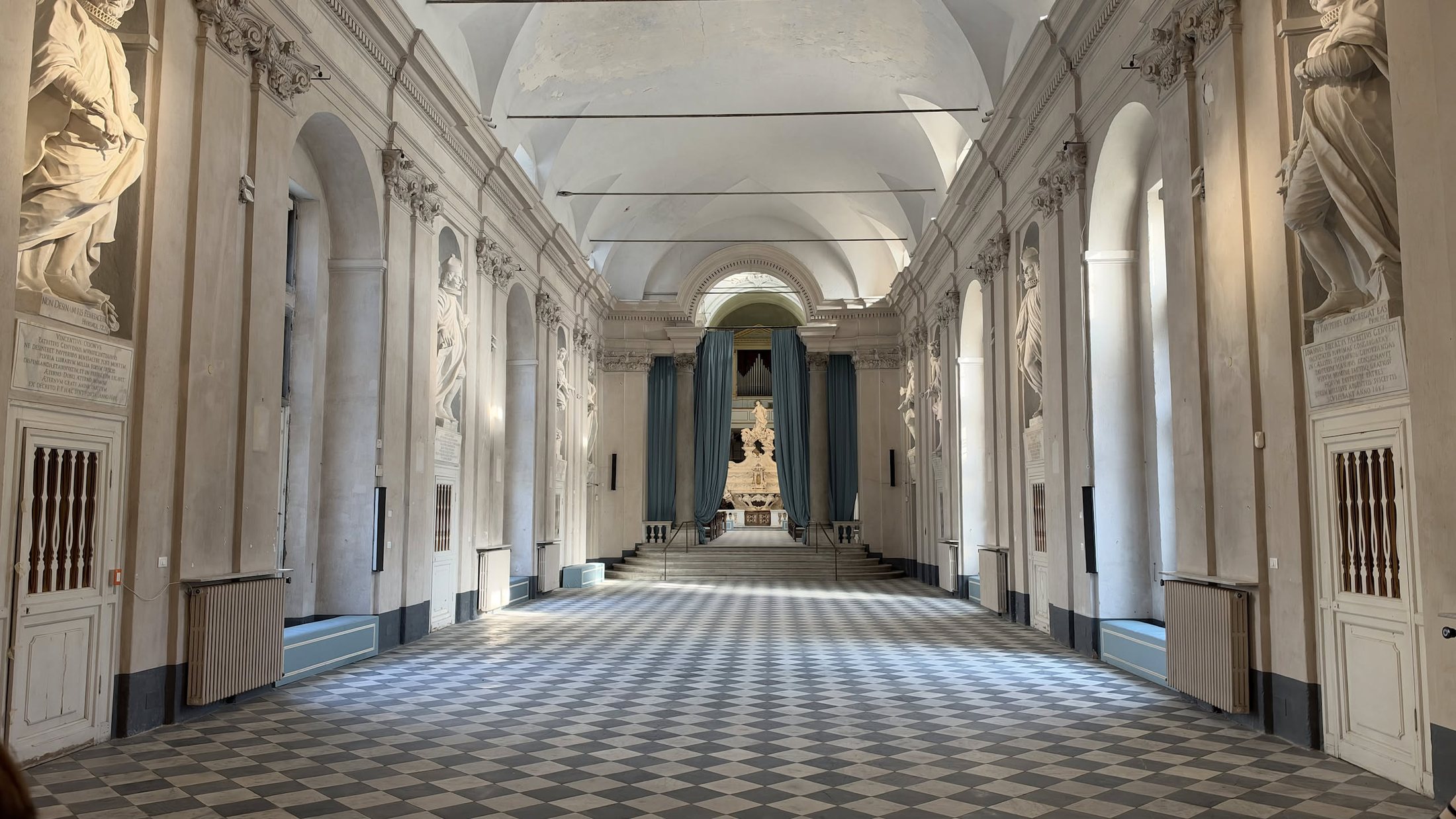 Una delle gallerie dell'Albergo dei Poveri: il pavimento a scacchi, le statue dei benefattori lungo le pareti e, in fondo, la cappella.
