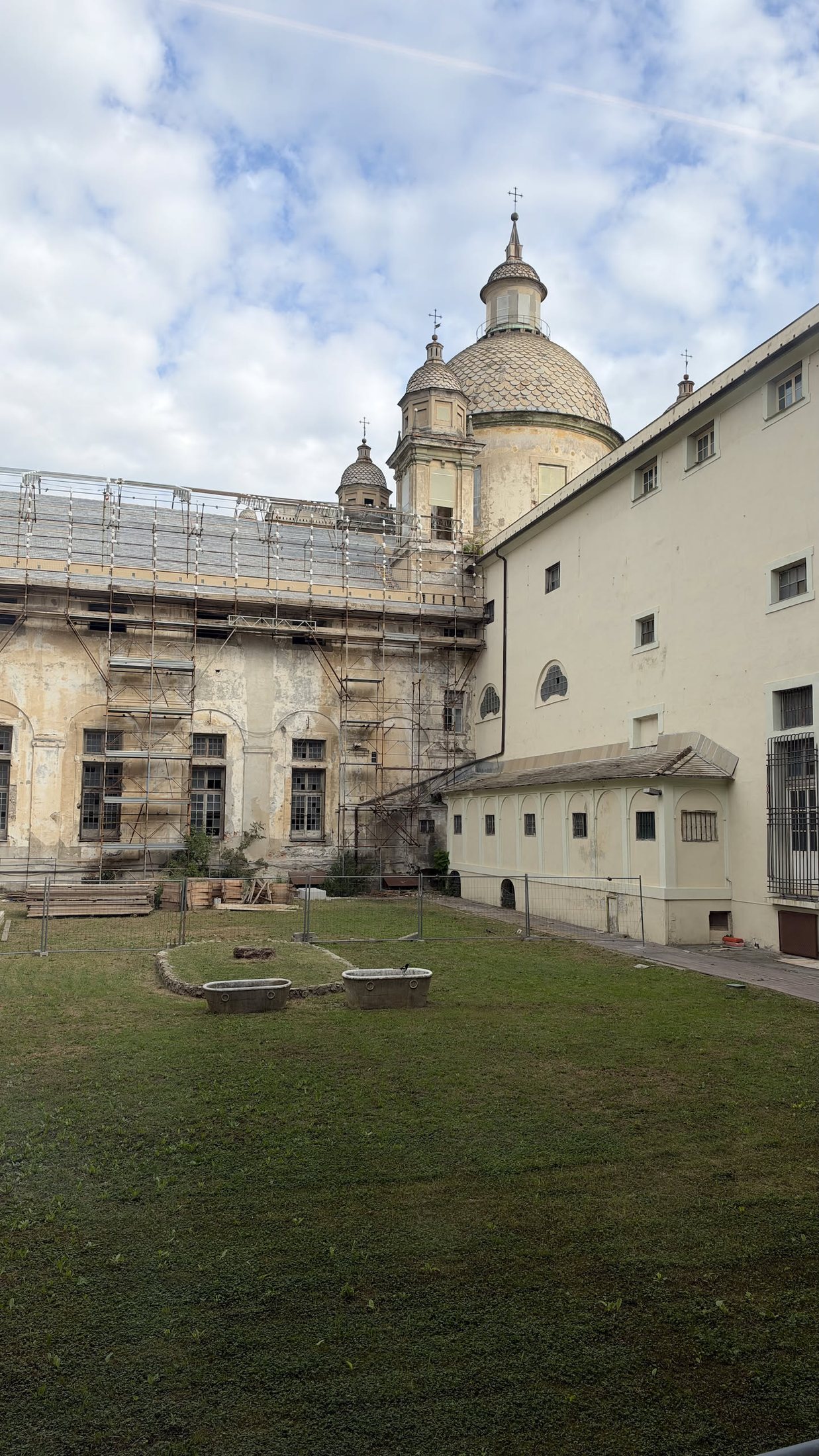 Uno dei cortili interni, col prato e la cupola della chiesa che spunta sopra i tetti.