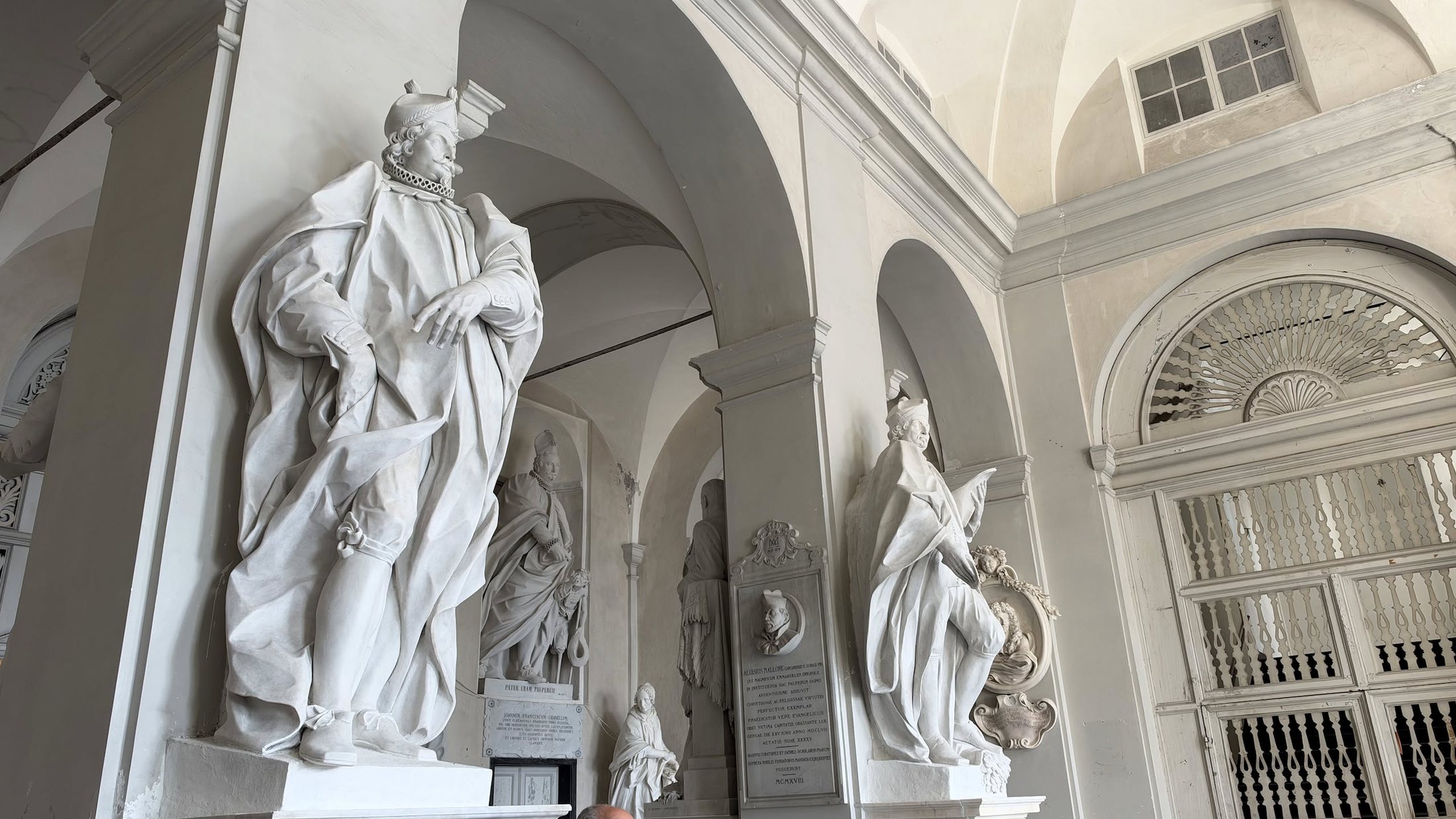 Sotto i portici, i benefattori in marmo, ognuno sul suo piedistallo.